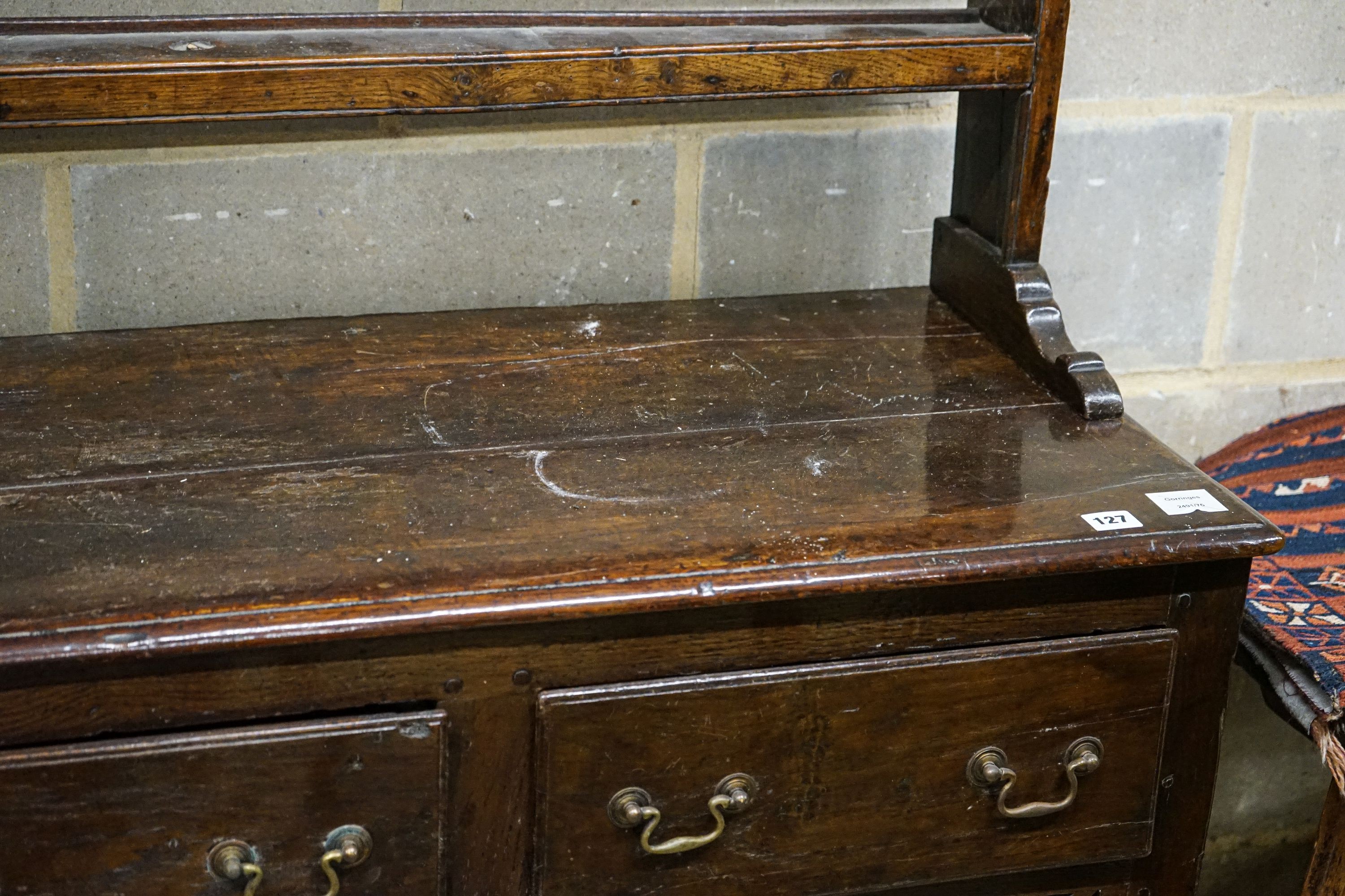 A mid 18th century oak dresser, with pierced cornice and three shelf rack over three drawers, with pierced frieze and turned and squared underframe, width 142cm, depth 46cm, height 204cm